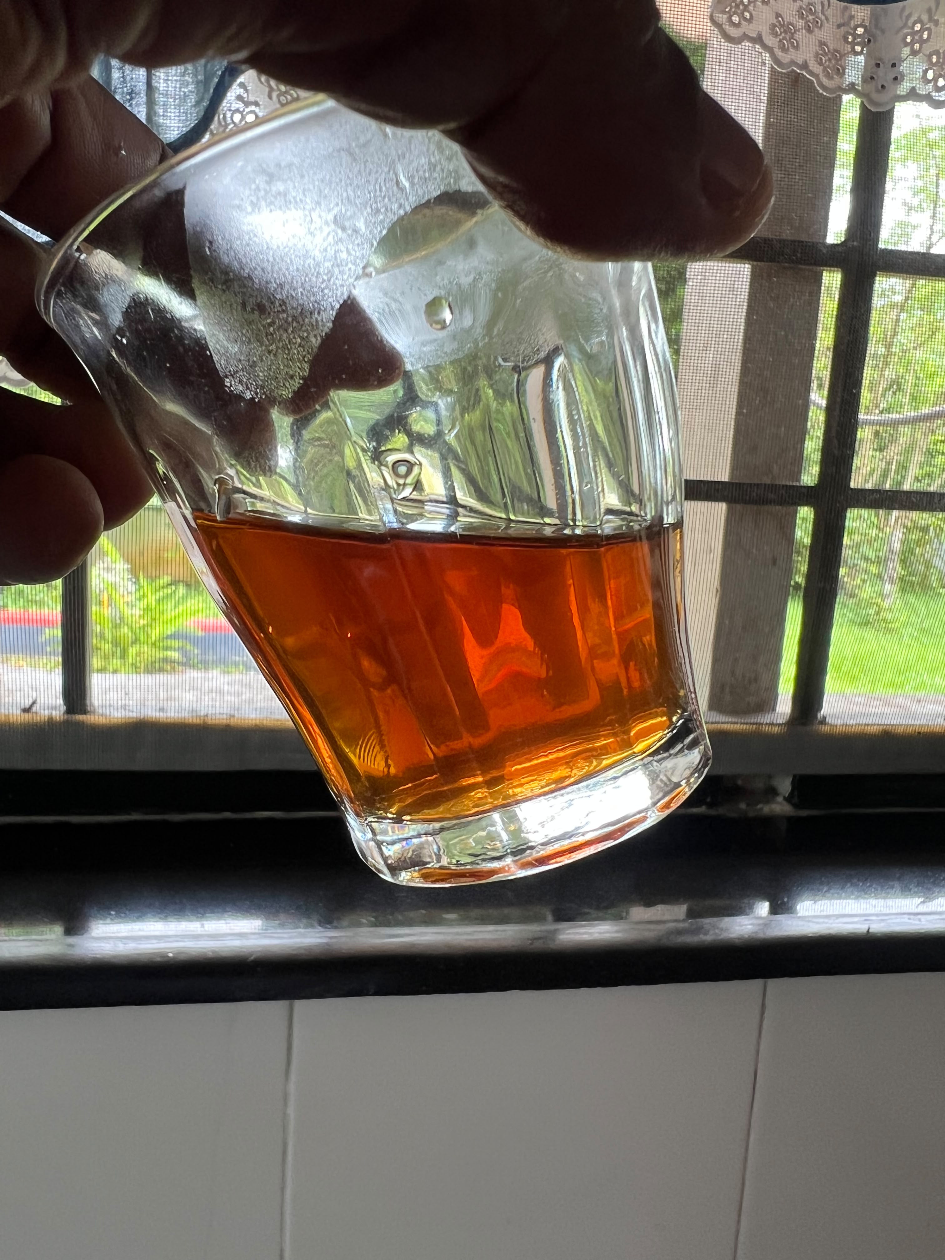 Final smoke-cured coffee leaf decoction showing clear amber liquor and dried leaves